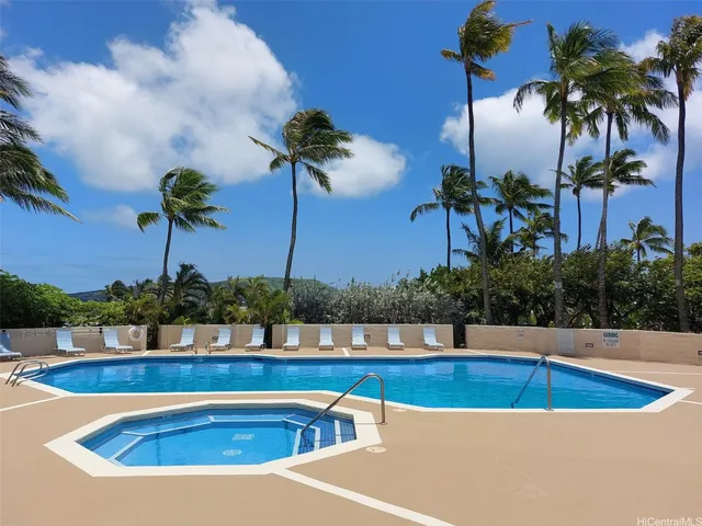 a view of swimming pool with outdoor seating and palm trees