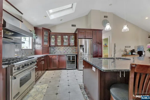 a large kitchen with stainless steel appliances granite countertop a stove a sink and a refrigerator