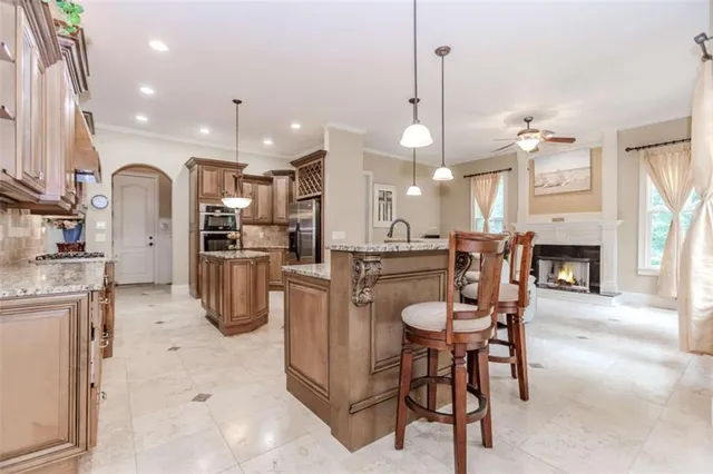 a kitchen with stainless steel appliances kitchen island granite countertop a refrigerator a stove a sink a dining table and chairs with wooden floor