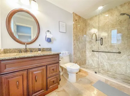 a spacious bathroom with a granite countertop toilet a sink and a mirror
