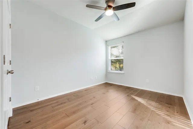 an empty room with a window and a ceiling fan