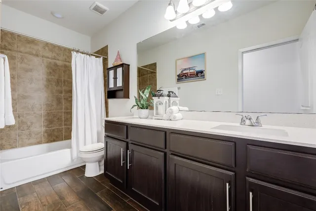 a bathroom with a double vanity sink a toilet and shower