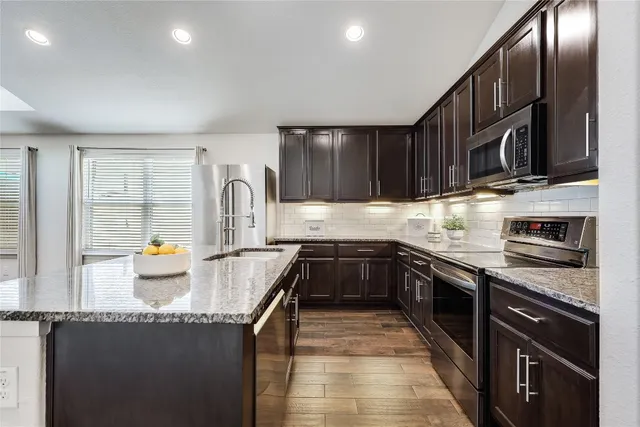 a kitchen with granite countertop a stove a sink and dishwasher a oven with wooden cabinets