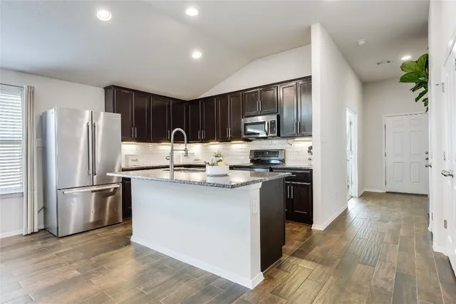 a kitchen with kitchen island granite countertop stainless steel appliances and wooden cabinets