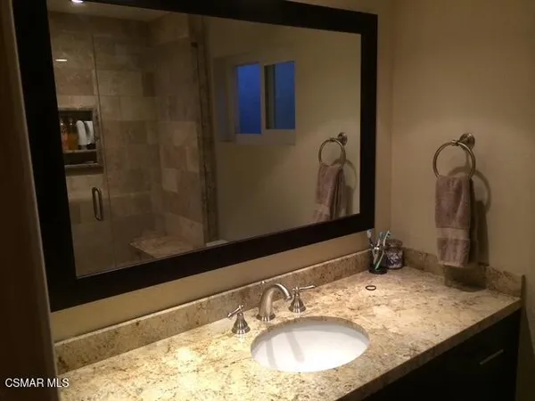 a bathroom with a granite countertop sink and a mirror