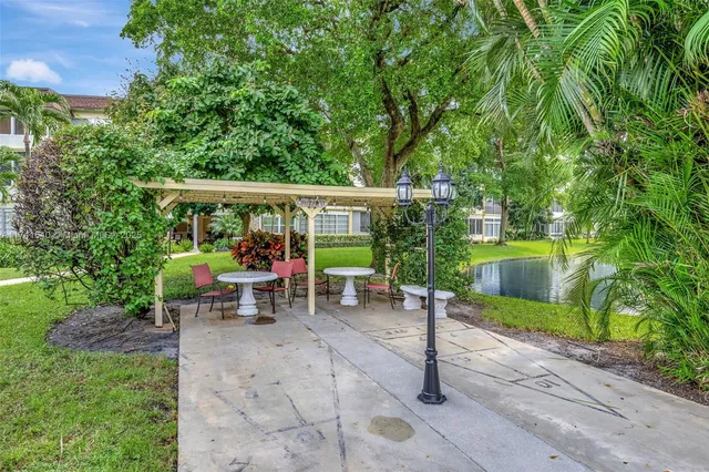 a view of a patio with table and chairs potted plants and large tree
