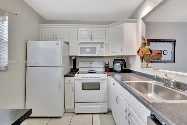 a kitchen with a refrigerator sink and white cabinets