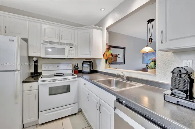 a kitchen with granite countertop a sink stainless steel appliances and cabinets