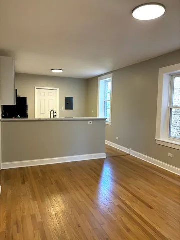 a view of kitchen and empty room with wooden floor