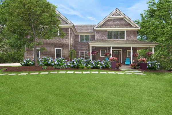 a front view of a house with garden and trees
