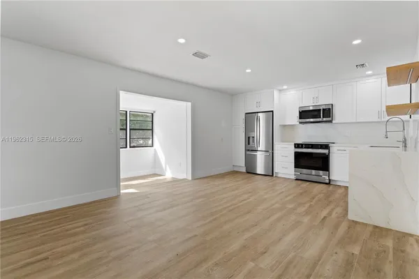 an empty room with wooden floor fireplace and windows