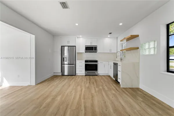 a view of a kitchen with wooden floor and a refrigerator