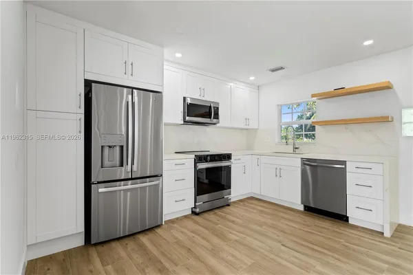 a kitchen with white cabinets and stainless steel appliances