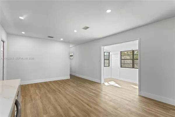 an empty room with wooden floor and windows