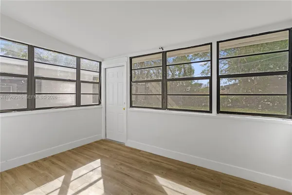 a view of an empty room with a window and wooden floor