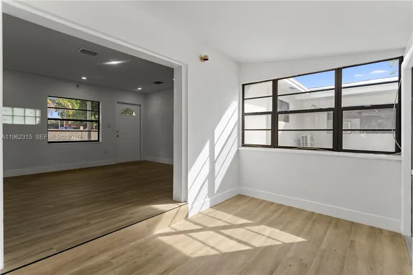 a view of an empty room with a window and wooden floor
