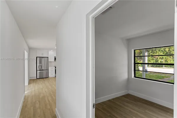 a view of empty room with wooden floor and fan