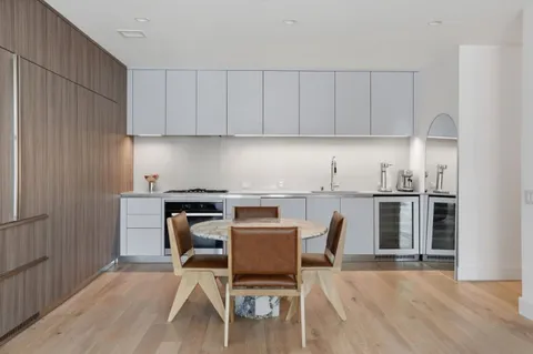 a kitchen with granite countertop a stove top oven a sink dishwasher and white cabinets with wooden floor