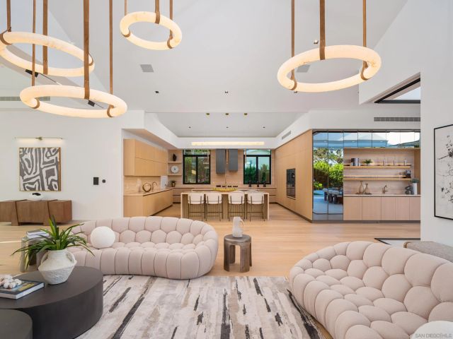 a living room with furniture kitchen view and a chandelier