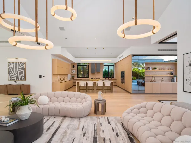 a living room with furniture kitchen view and a chandelier