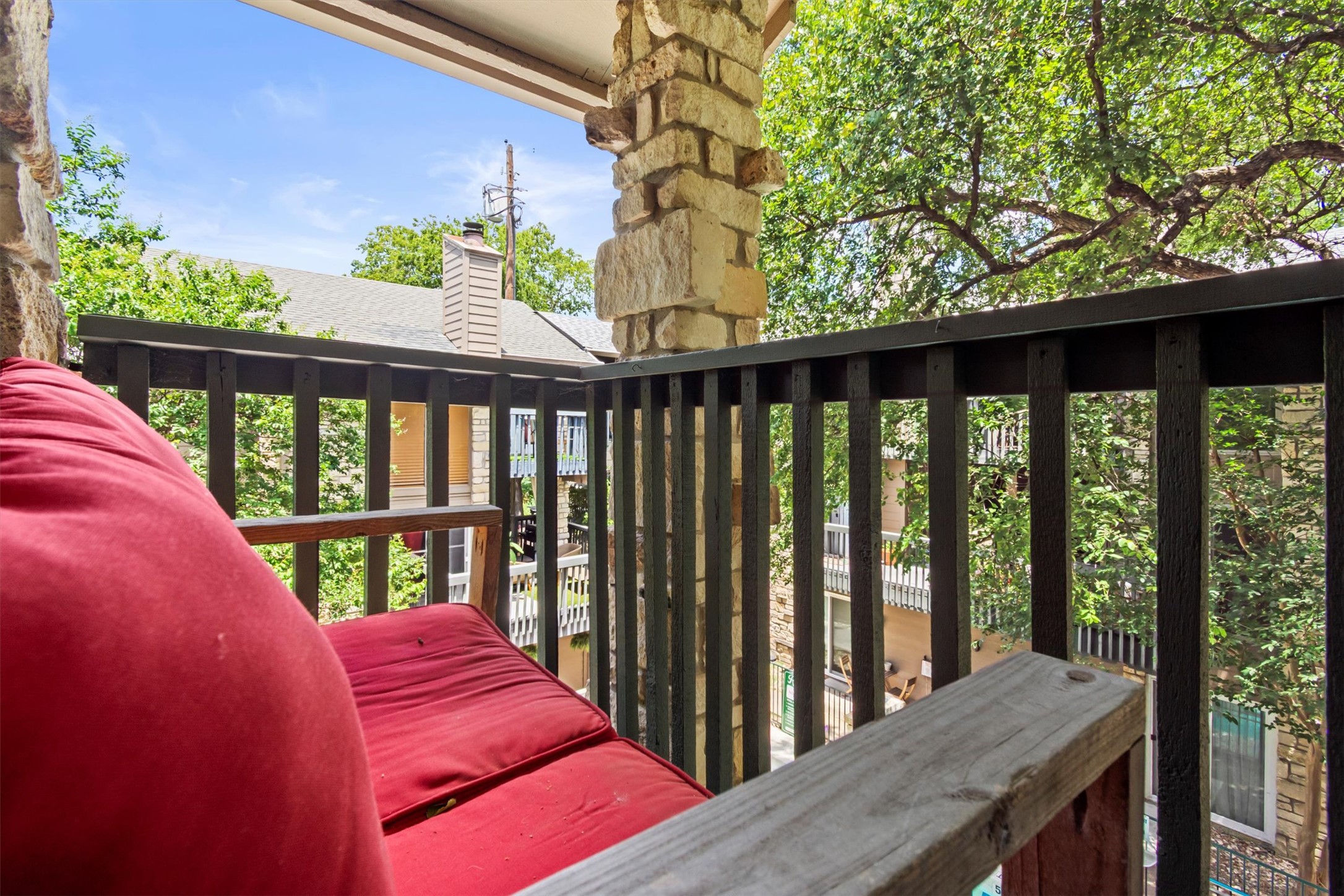 3627 Menchaca Road, Unit 204 Austin, TX 78704 - Photo 16 of 23 Relax on this peaceful balcony, featuring a stone column and a serene, tree-filled view.