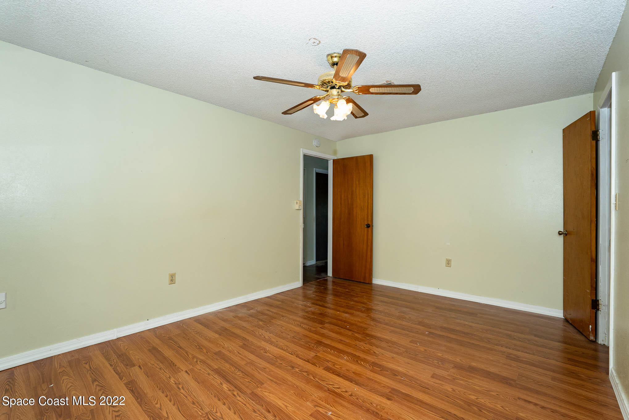 447 Count Street Melbourne, FL 32901 - Photo 11 of 24 a view of an empty room with wooden floor and a ceiling fan