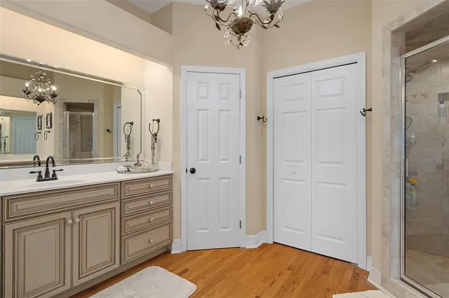 a bathroom with a sink a light fixture and a glass door shower