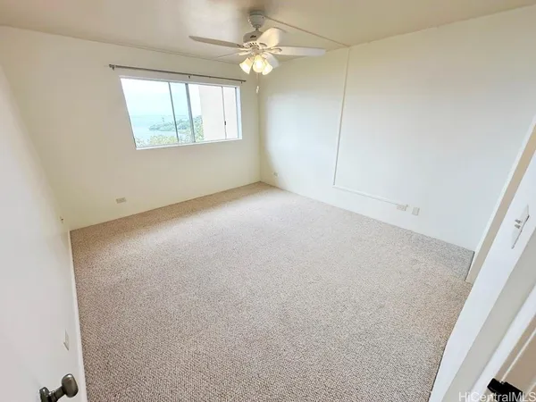 an empty room with windows and fan