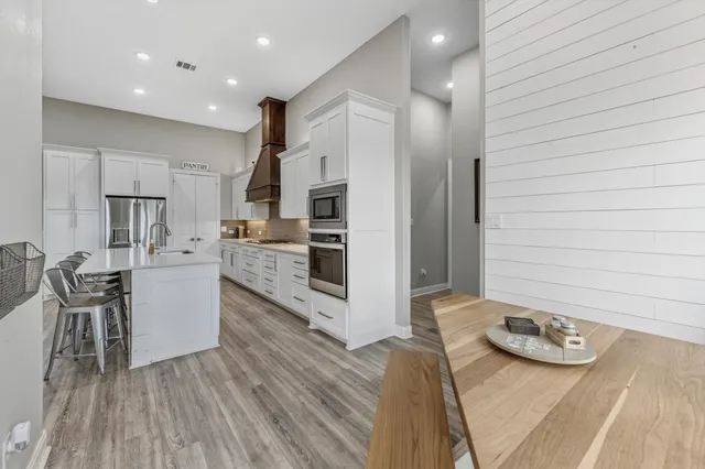 a spacious bedroom with a bed a dresser and a chandelier