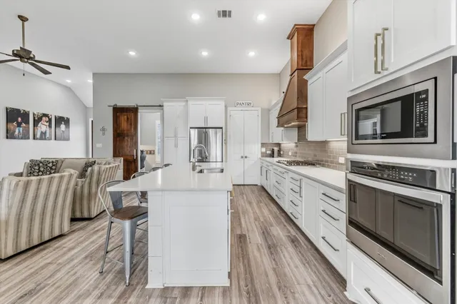 a large kitchen with stainless steel appliances granite countertop a lot of counter space and wooden floors