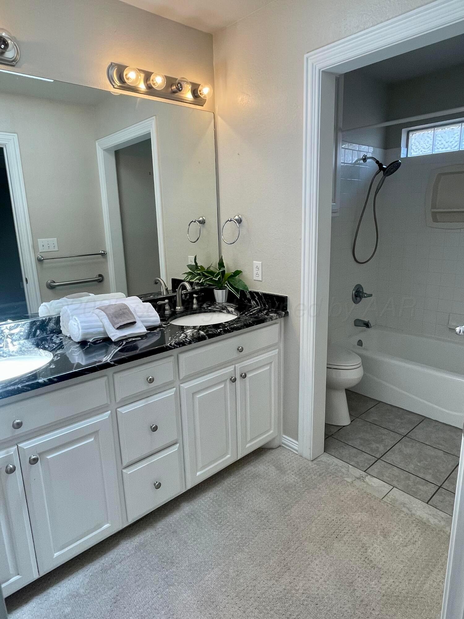522 Carson Avenue Dumas, TX 79029 - Photo 11 of 18 a spacious bathroom with double sink a toilet a shower and a mirror