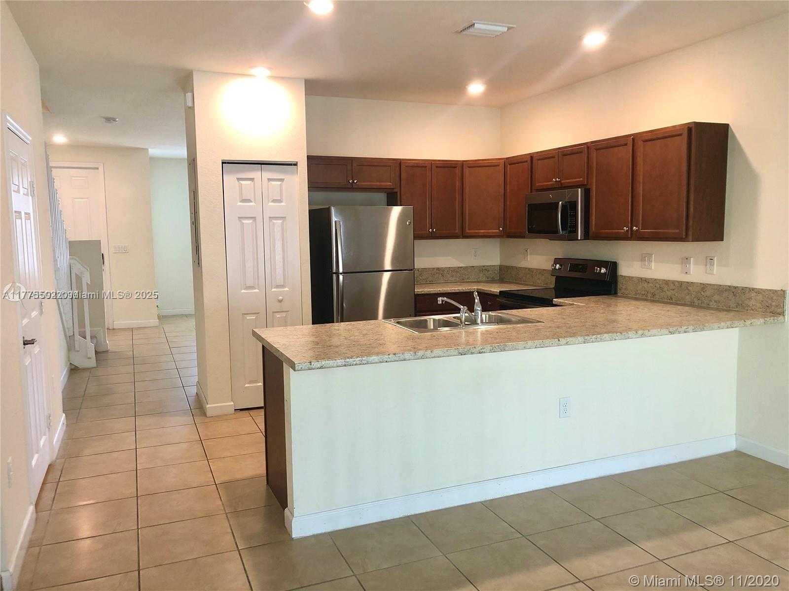 9213 West 33rd Way Hialeah, FL 33018 - Photo 2 of 13 a kitchen with a sink a refrigerator and a stove top oven