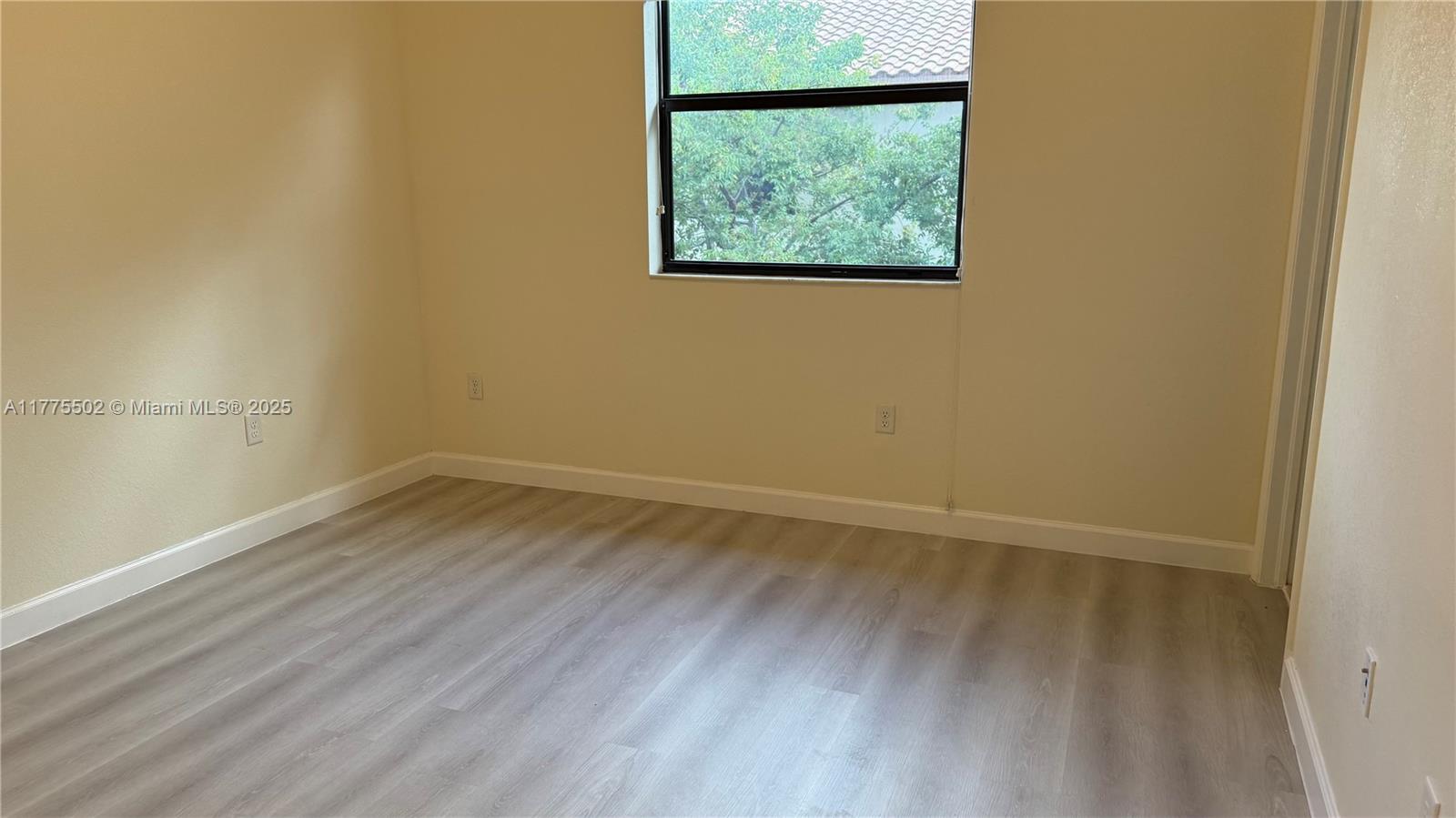 9213 West 33rd Way Hialeah, FL 33018 - Photo 9 of 13 an empty room with a wooden floor and window