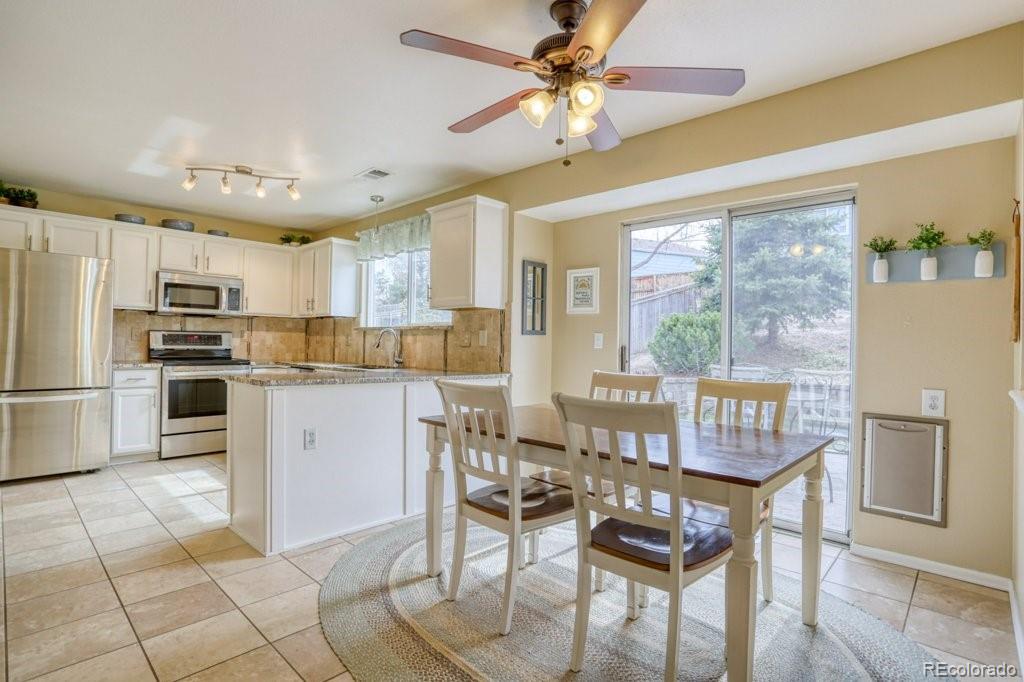 9561 South Castle Ridge Circle Highlands Ranch, CO 80129 - Photo 8 of 29 a kitchen with kitchen island granite countertop a counter space dining table and stainless steel appliances