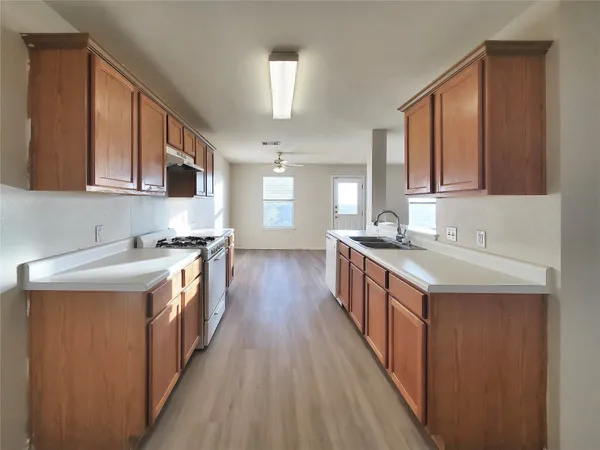 a kitchen with stainless steel appliances granite countertop a stove a sink dishwasher and a refrigerator with wooden cabinets