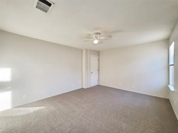 an empty room with a ceiling fan and carpet