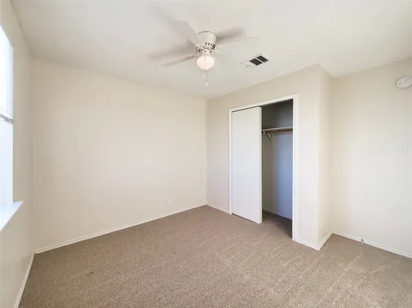 an empty room with a ceiling fan and a window