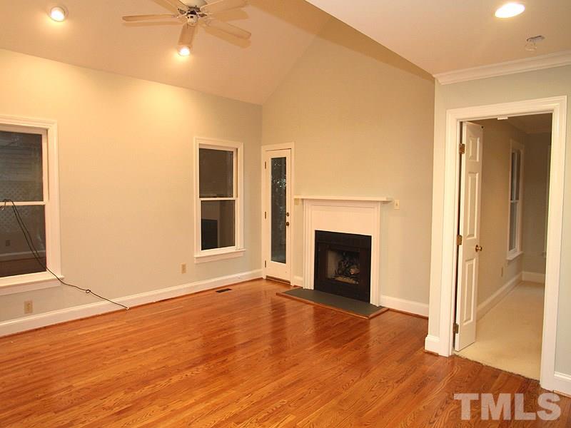 2109 Camrose Street Raleigh, NC 27608 - Photo 4 of 12 an empty room with wooden floor a fireplace and entryway