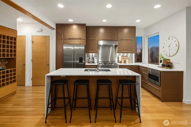 a kitchen with stainless steel appliances kitchen island granite countertop a table chairs sink and wooden floor