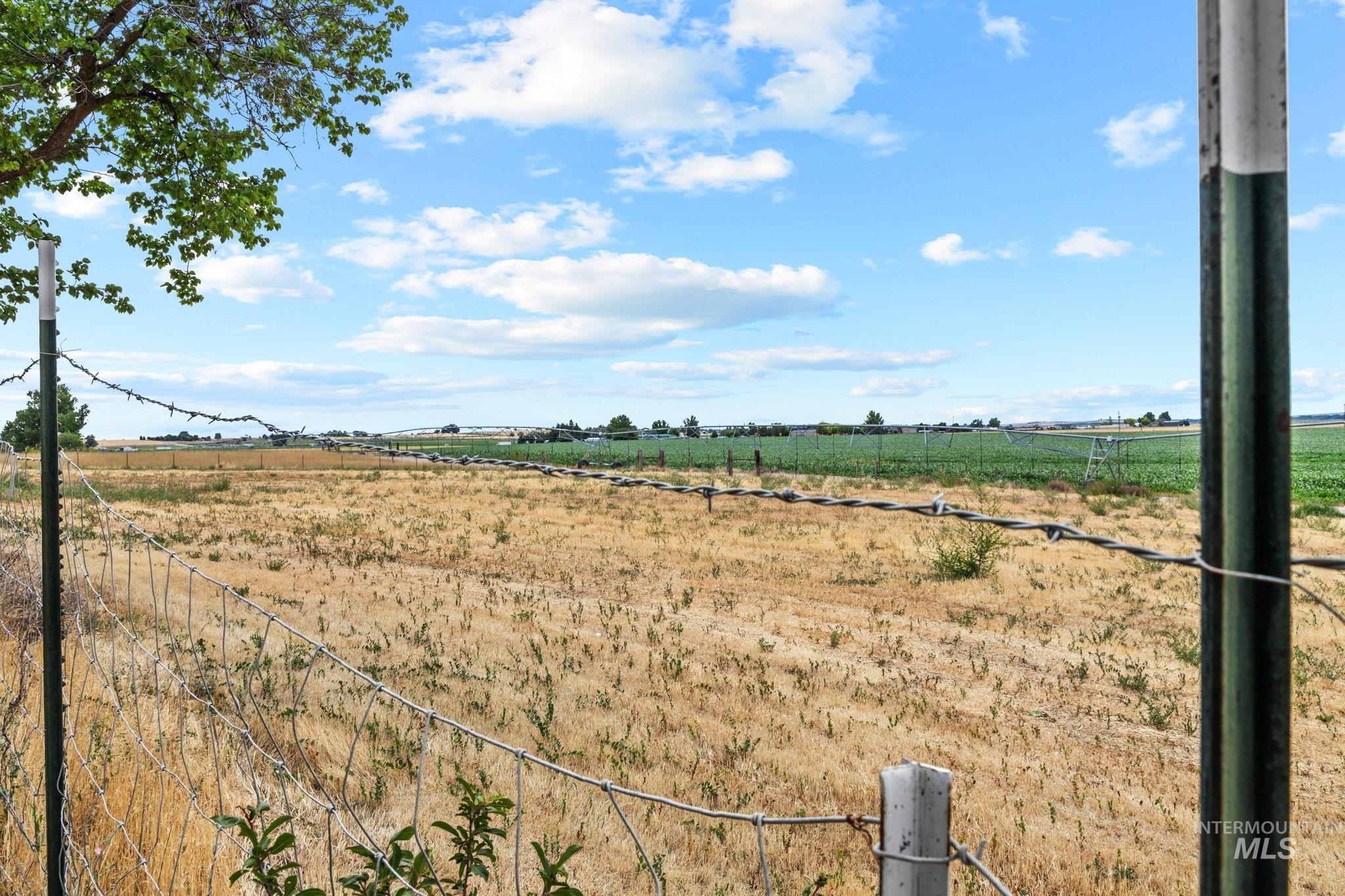 18338 Pride Lane Caldwell, ID 83607 - Photo 43 of 50 Expansive agricultural landscape featuring a barbed wire fence and distant green fields under a clear sky