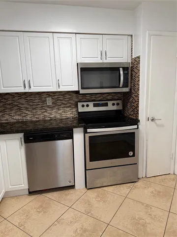 a kitchen with granite countertop white cabinets and stainless steel appliances