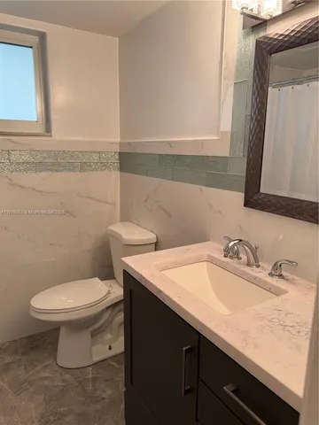 a bathroom with a granite countertop sink and a toilet