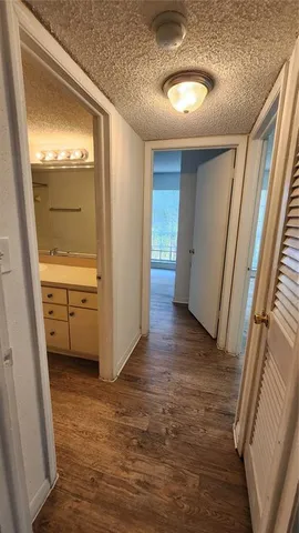a view of a hallway with wooden floor and cabinets