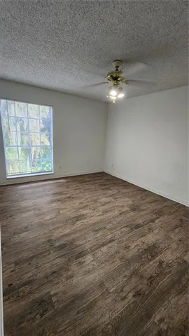 an empty room with ceiling fan and window
