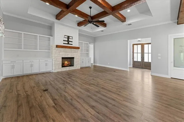 an empty room with wooden floor fireplace and windows