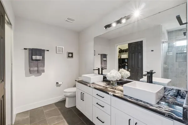 a bathroom with a granite countertop sink a toilet a mirror and shower