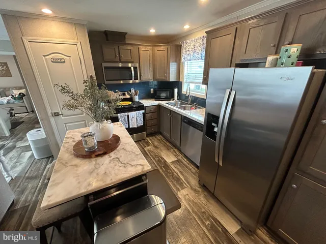 a kitchen with stainless steel appliances granite countertop a refrigerator a stove and a sink