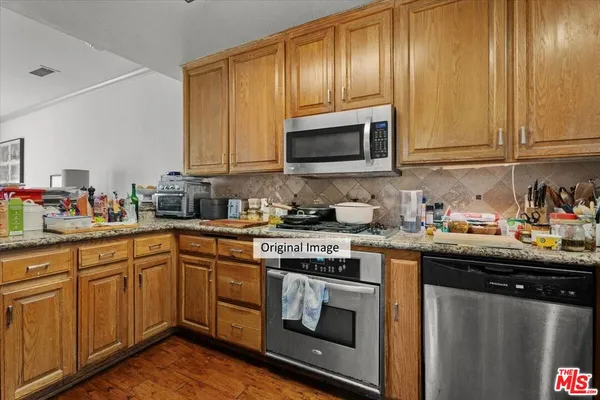 a kitchen with granite countertop wooden cabinets and stainless steel appliances