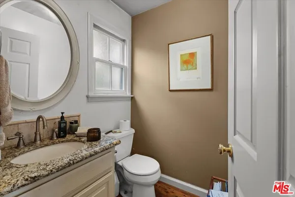 a bathroom with a granite countertop toilet a sink and a mirror