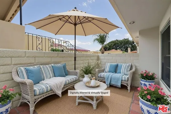 a view of a patio with couches table and chairs under an umbrella